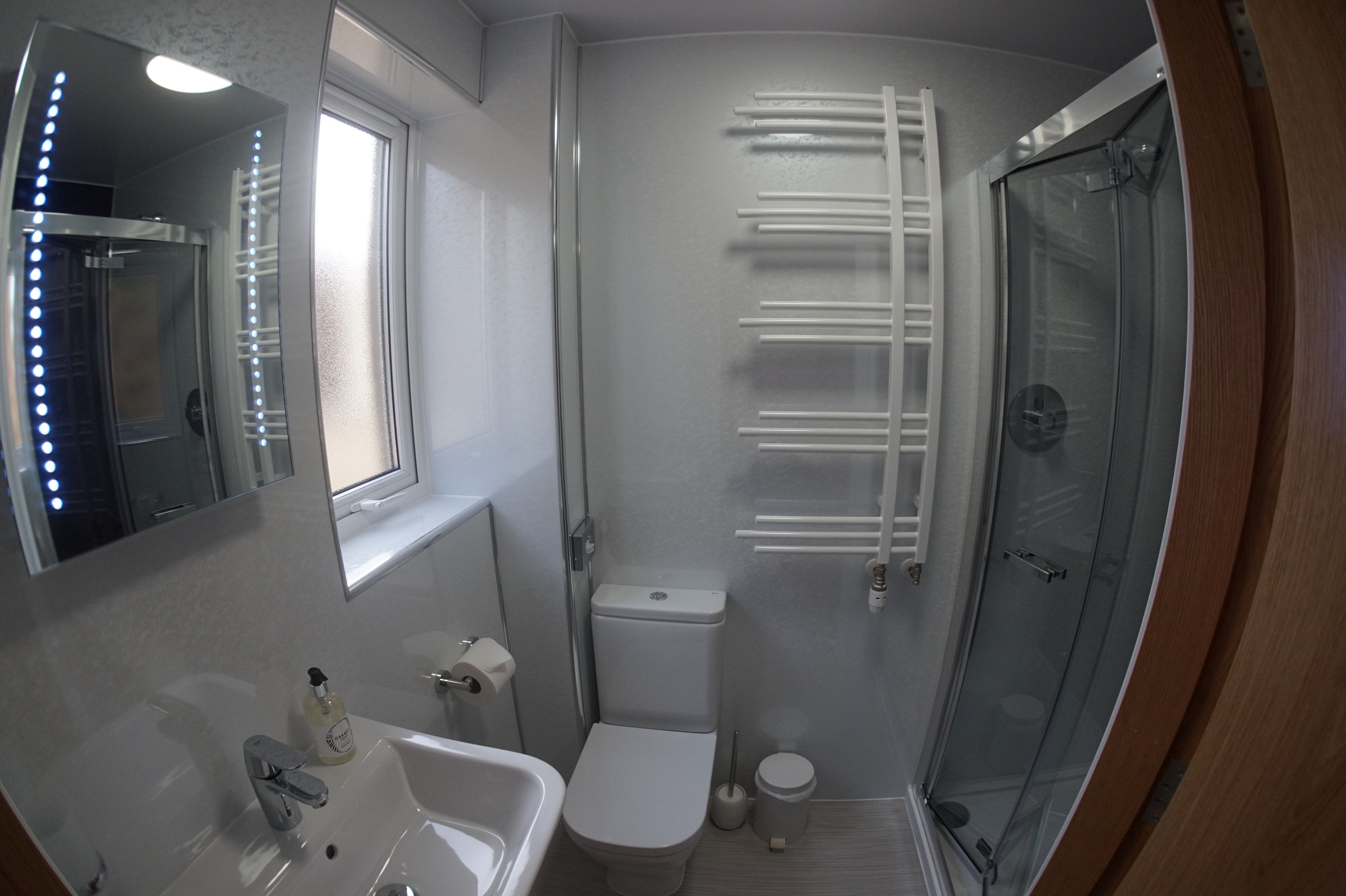A compact bathroom with a sink, toilet, and glass shower enclosure.