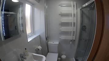 A compact bathroom with a sink, toilet, and glass shower enclosure.