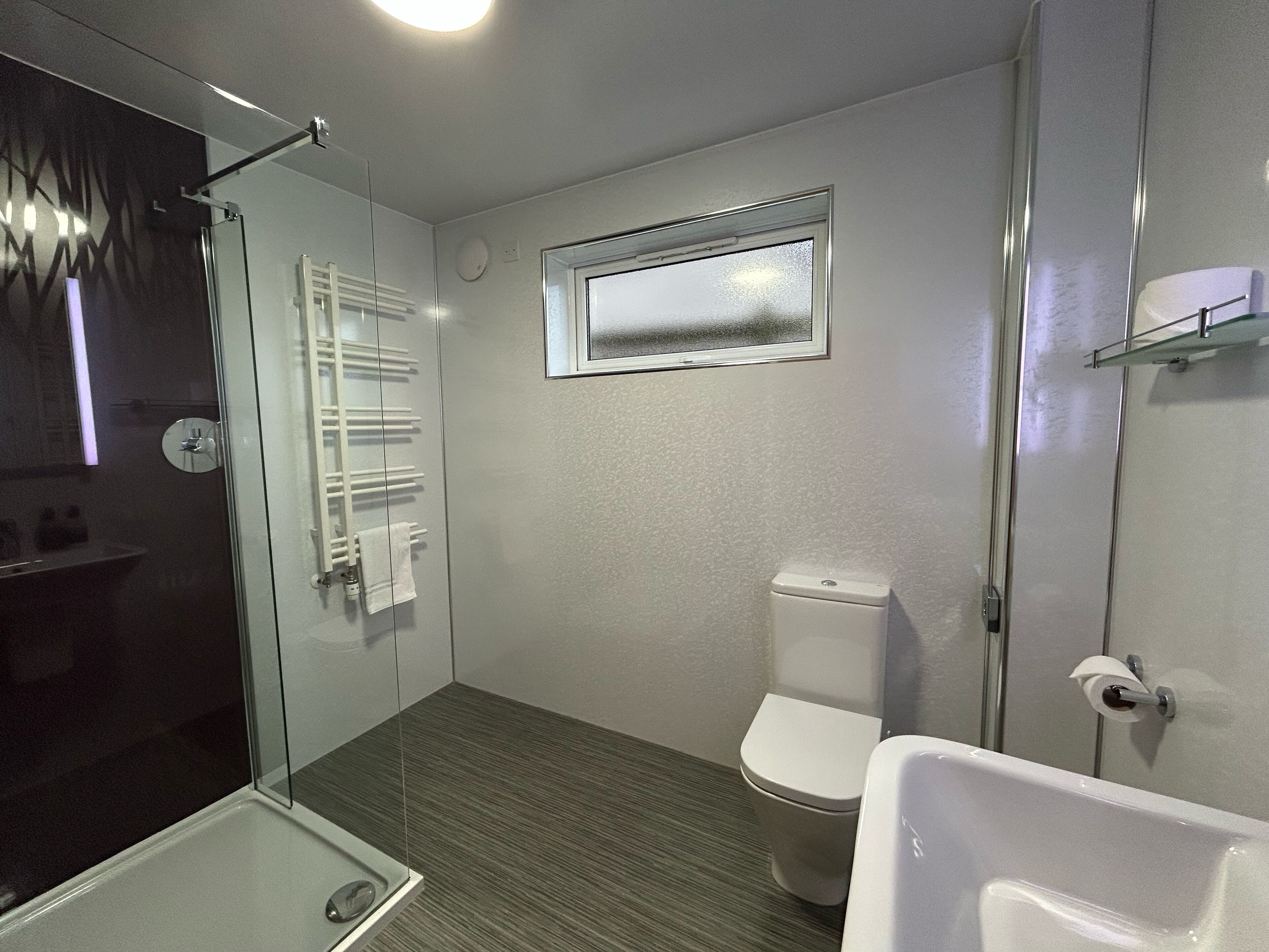 Une salle de bain moderne avec une douche à parois de verre, des toilettes et une baignoire.