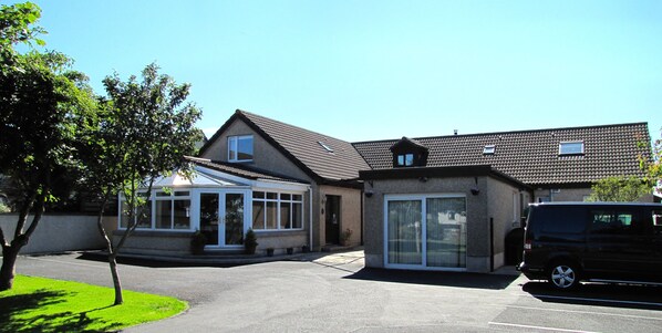 Ein zweistöckiges Haus mit Garage, überdachter Terrasse und Auffahrt.