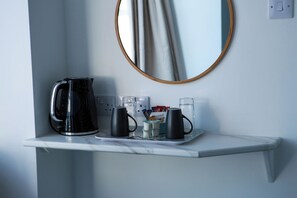 Eine Kaffeestation mit Wasserkocher, zwei Tassen und einer Tablett mit Bechern und einem Taschentuchkarton.