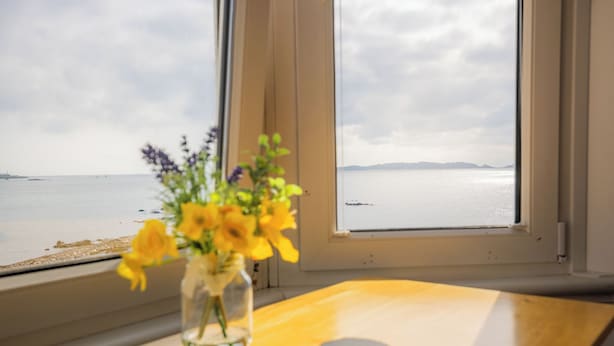 Une table en bois sur laquelle se trouve un vase rempli de fleurs jaunes et deux objets ronds.