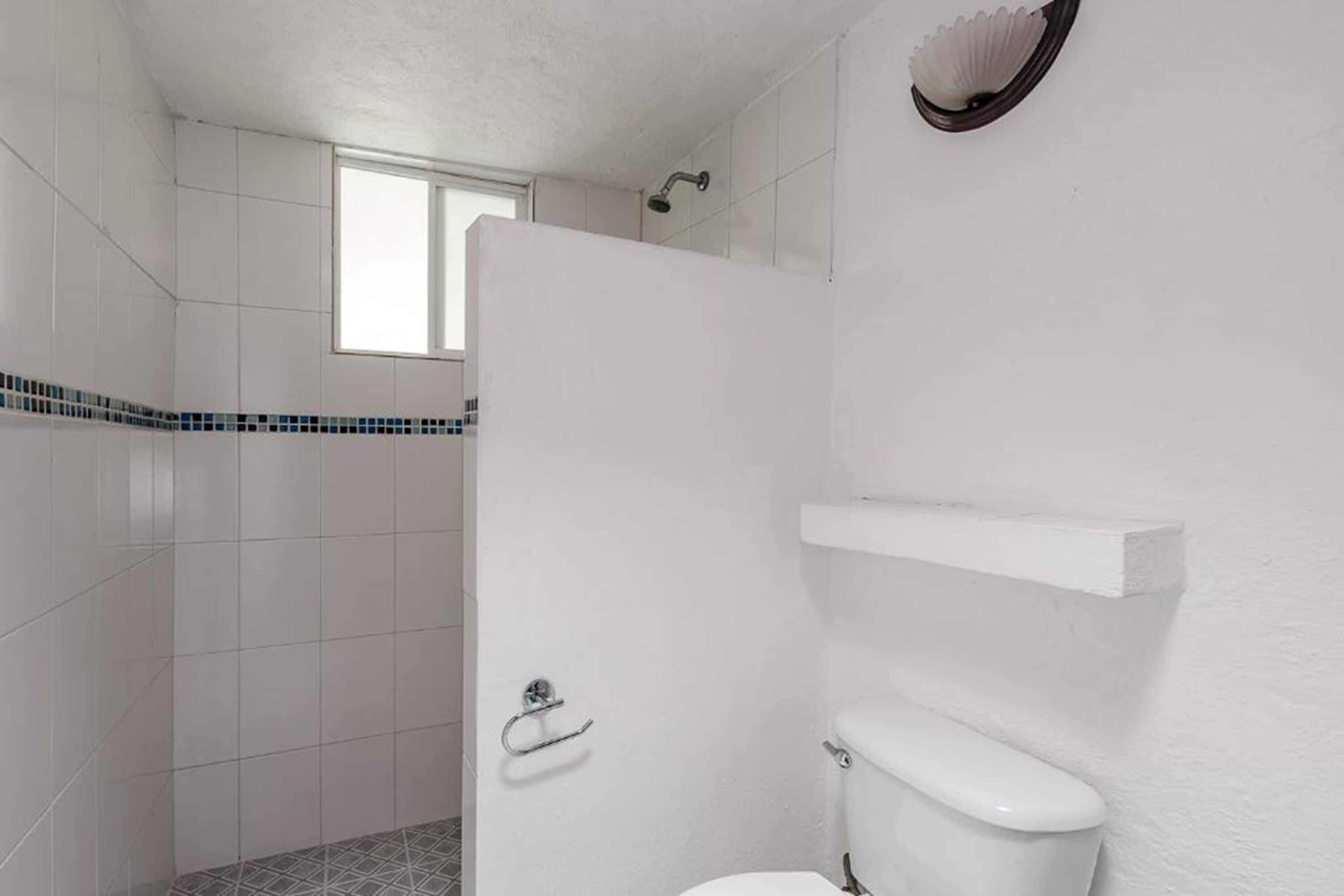 Un baño con inodoro, ducha y ventana.