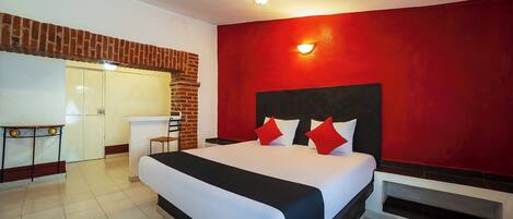 Una habitación de hotel con una cama grande, un escritorio, una pared de acento roja y una chimenea de ladrillo.