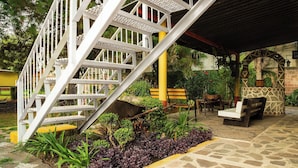A staircase leading to a covered outdoor area with seating and plants. - Capital O Hotel Meson Del Rio, Tepotzotlan (Tepotzotlán)
