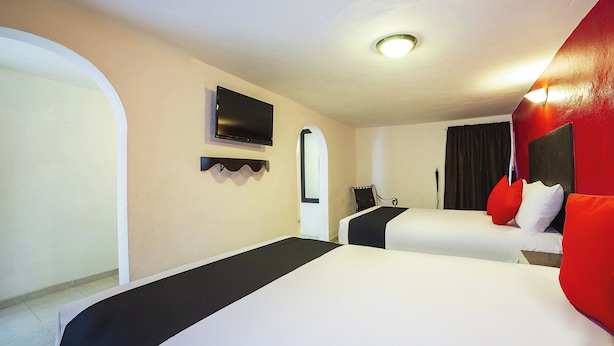 Une chambre d’hôtel avec deux lits, une télévision, un miroir et un mur d’accent de couleur rouge.