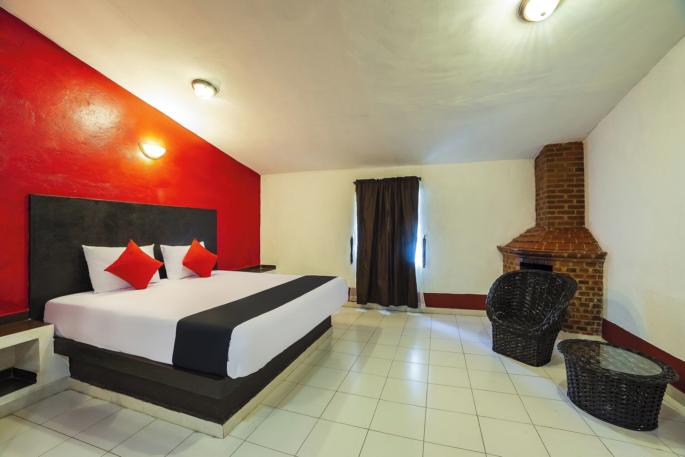 Una habitación de hotel con una cama grande, una chimenea de ladrillo y una pequeña zona de estar.