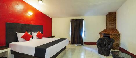 Una habitación de hotel con una cama grande, una chimenea de ladrillo y una pequeña zona de estar.
