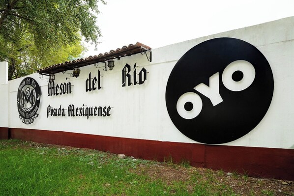 Egy fal, amelyen a „Mesón del Río” és a „Posada Mexicana” felirat szerepel, valamint egy nagy, fekete-fehér „OYO” logó.