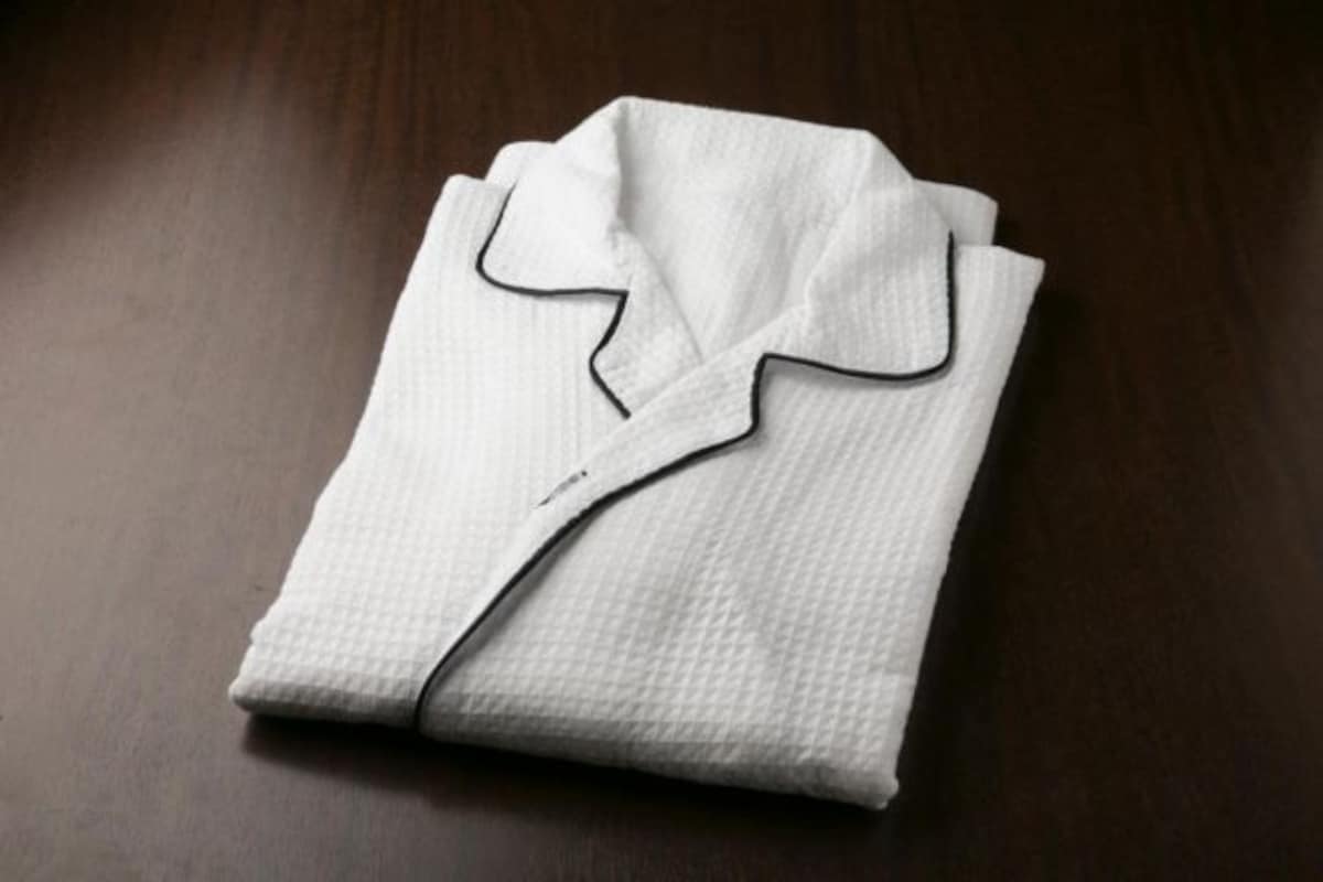 A neatly folded white shirt on a dark wooden surface.