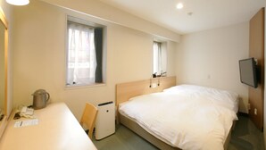 A hotel room with a bed, a desk, a chair, a small table, a kettle, a TV, and a window with curtains. - Ace Inn Matsumoto (Matsumoto)