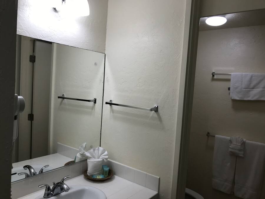 A bathroom with a sink, mirror, towel rack, and a towel hanging on the wall.