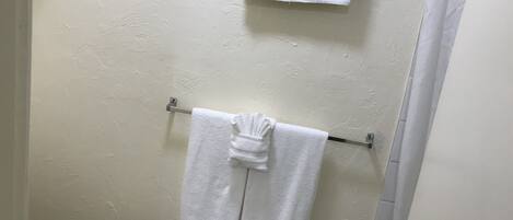A bathroom with a toilet, a towel rack with two white towels, and a shower curtain.