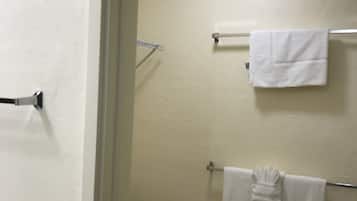 A bathroom with a toilet, a towel rack with two towels, and a shower curtain rod.
