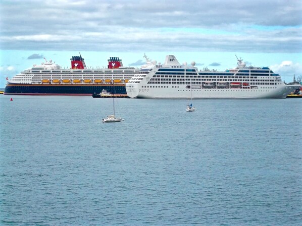 A large cruise ship docked at a port with a smaller sailboat nearby.