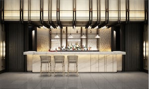 A bar area with a marble countertop, two wicker bar stools, and a variety of bottles and glasses.