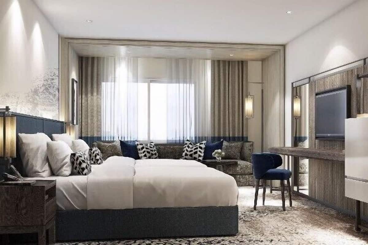 A modern hotel room with a large bed, a desk, and a TV.
