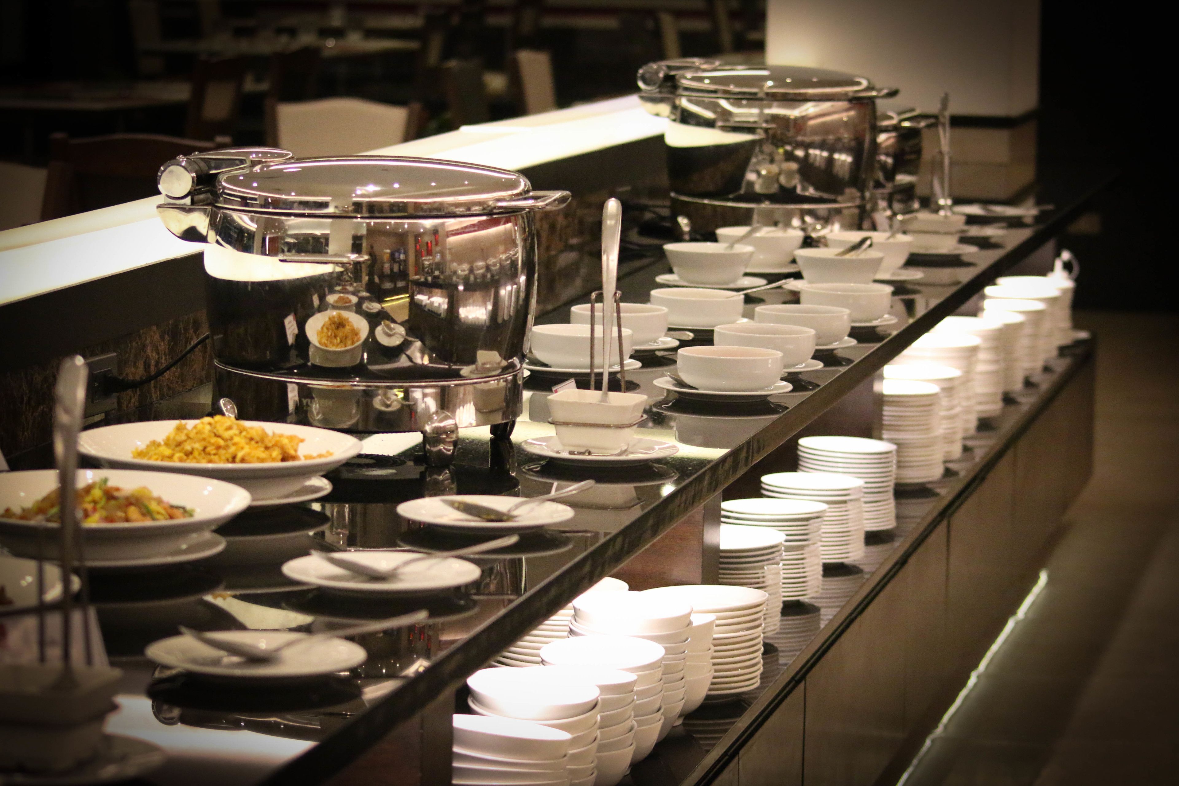 A buffet setup with multiple serving stations, including hot and cold food options, arranged along a long counter.
