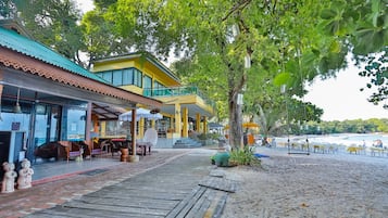 Un restaurant situé en bord de mer, doté d’une terrasse et d’une jetée en bois qui mène à la plage.