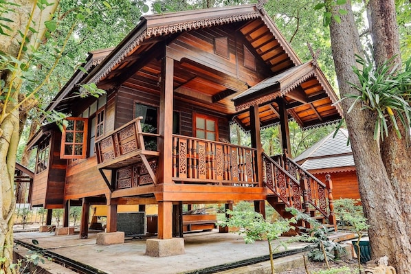 Une maison en bois dotée d’un balcon, entourée d’arbres.