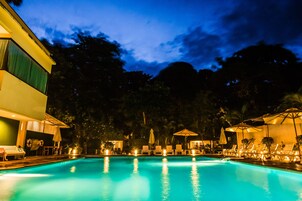 Una piscina al aire libre, sillones reclinables de piscina