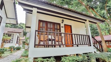 A two-story building with a balcony, a wooden door, and a small garden area.