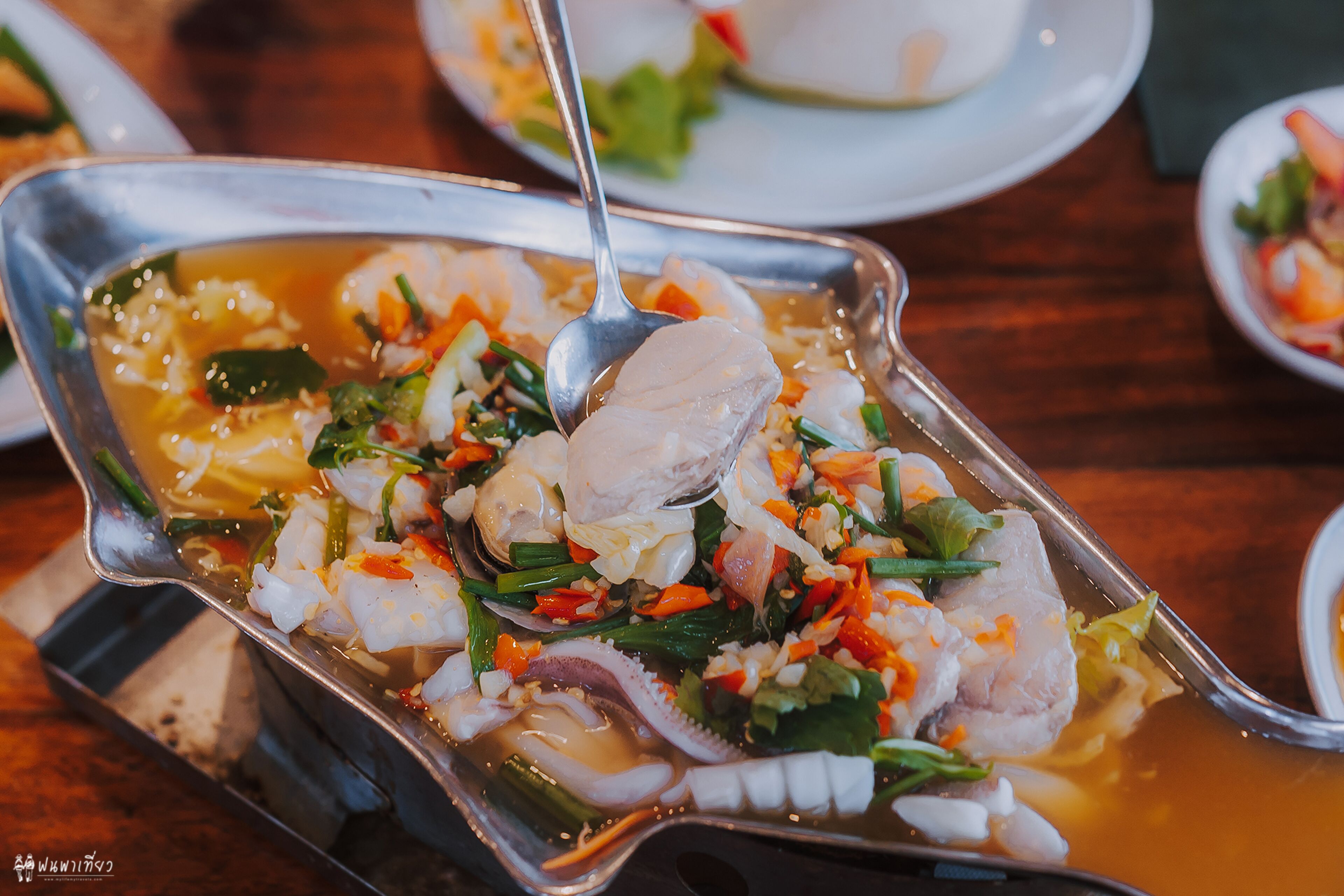 A dish with seafood and vegetables in a metal serving dish.