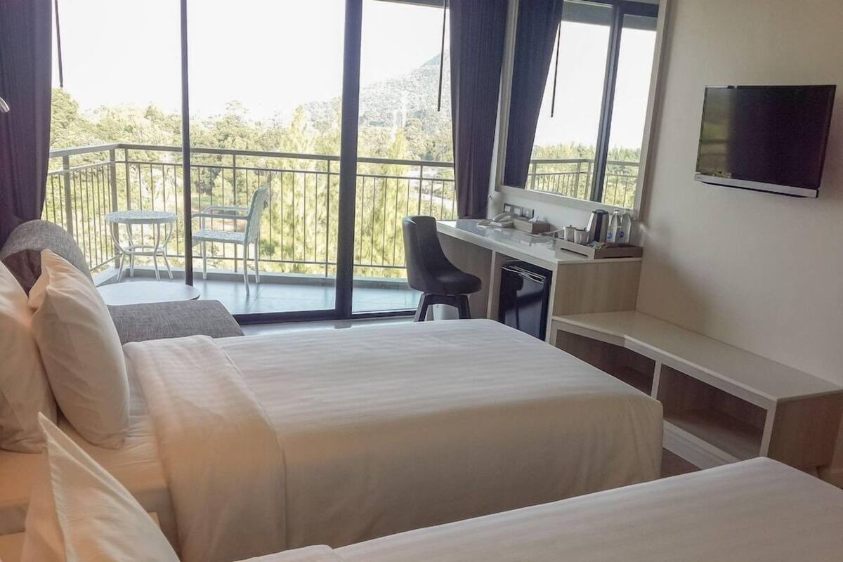 A hotel room with two beds, a desk, a chair, and a TV.