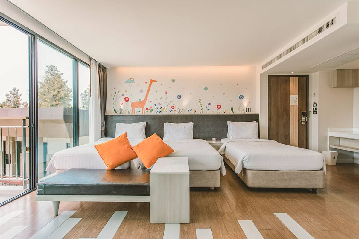 A modern hotel room with two beds, a sofa, and a large window.
