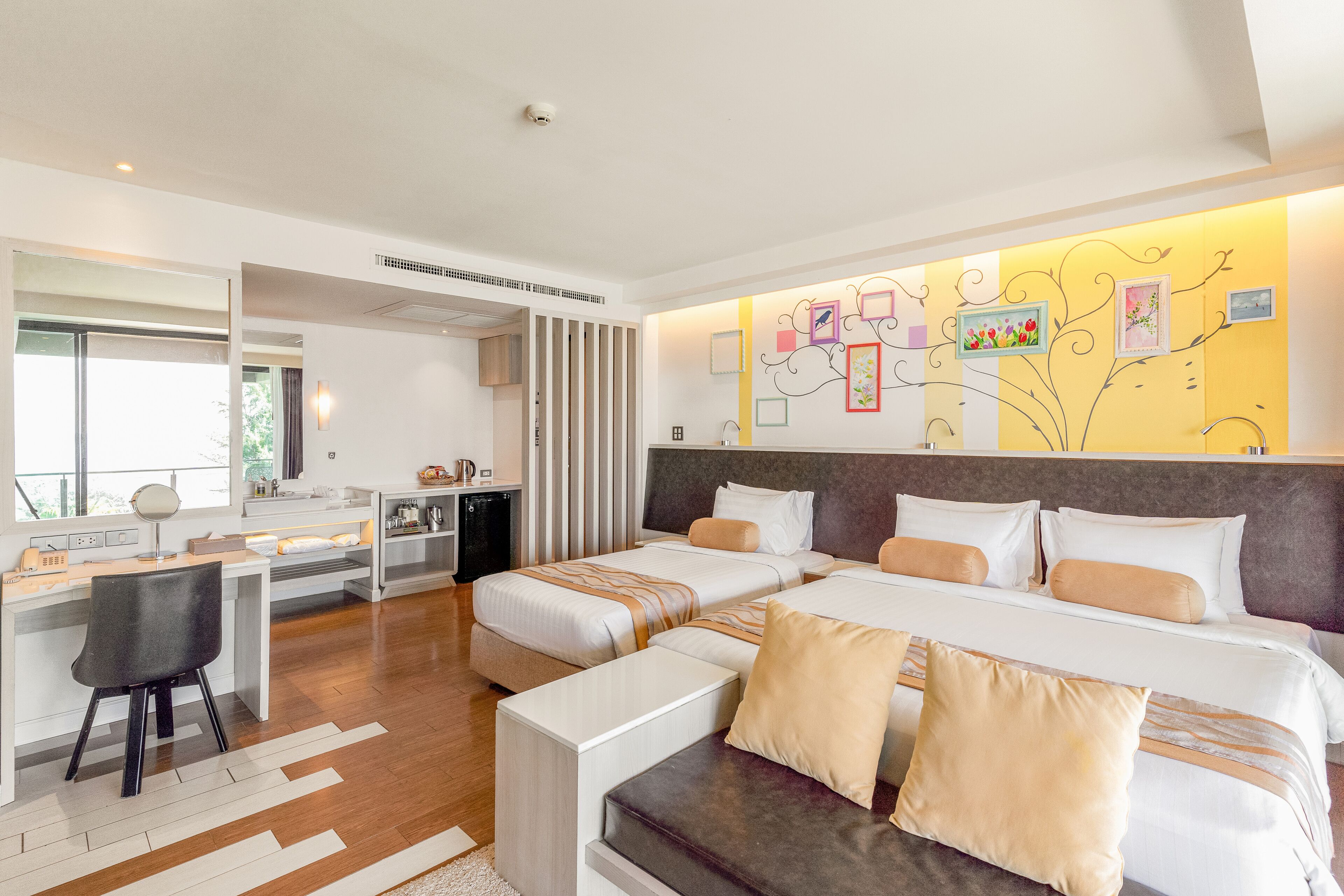 A modern hotel room with two beds, a desk, and a seating area.
