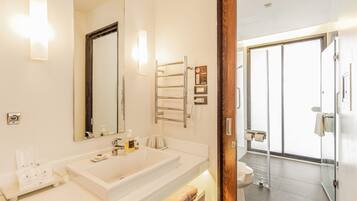 A modern bathroom with a large mirror, white sink, and a glass shower door.
