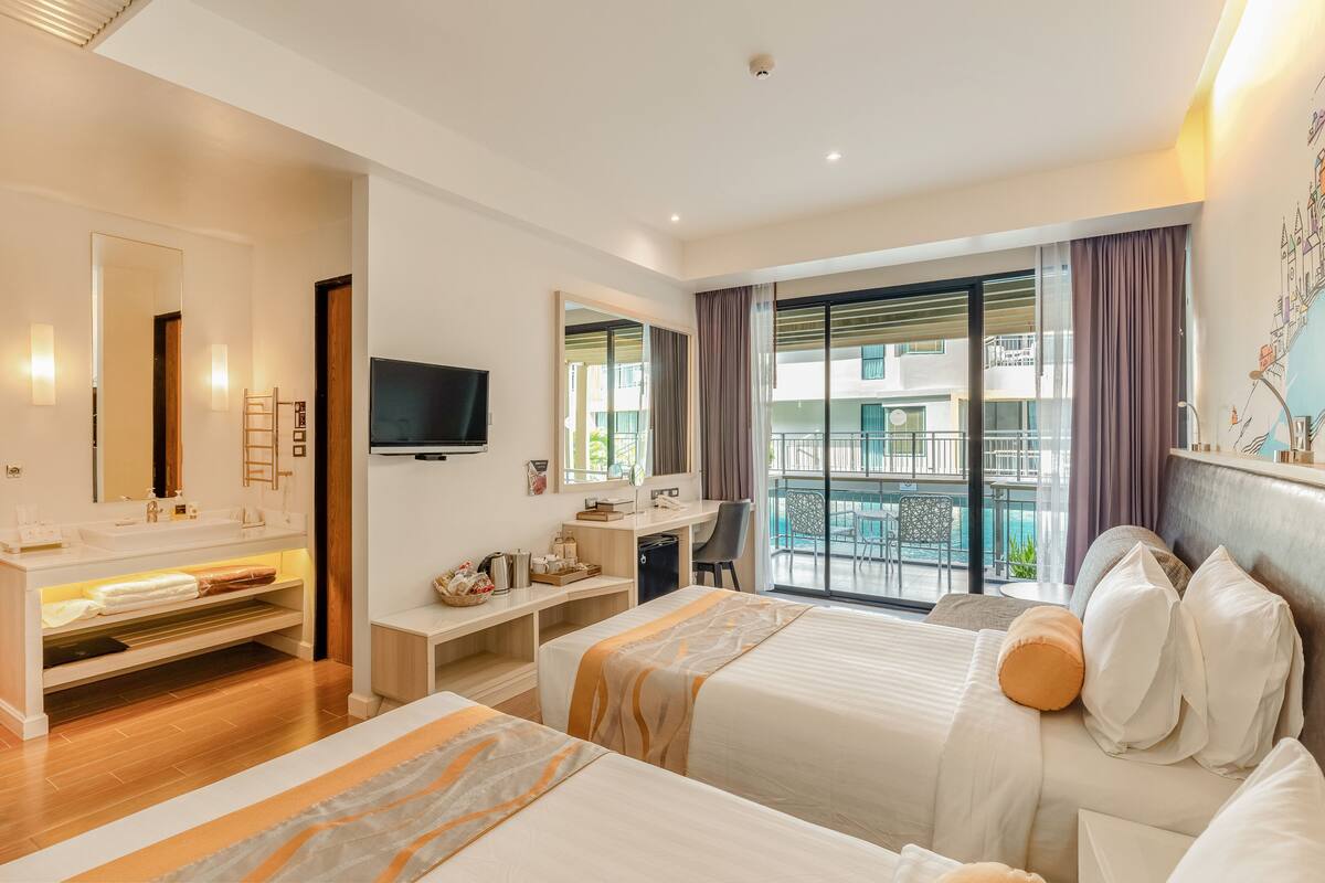 A hotel room with two beds, a desk, a TV, a balcony with a pool view, and a large window with curtains.
