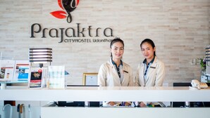 A reception desk at a hotel with a logo above and a framed certificate below. - Prajaktra City Hostel (Udon Thani)