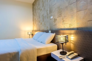 A hotel room with a bed, bedside lamp, and a phone on a nightstand.