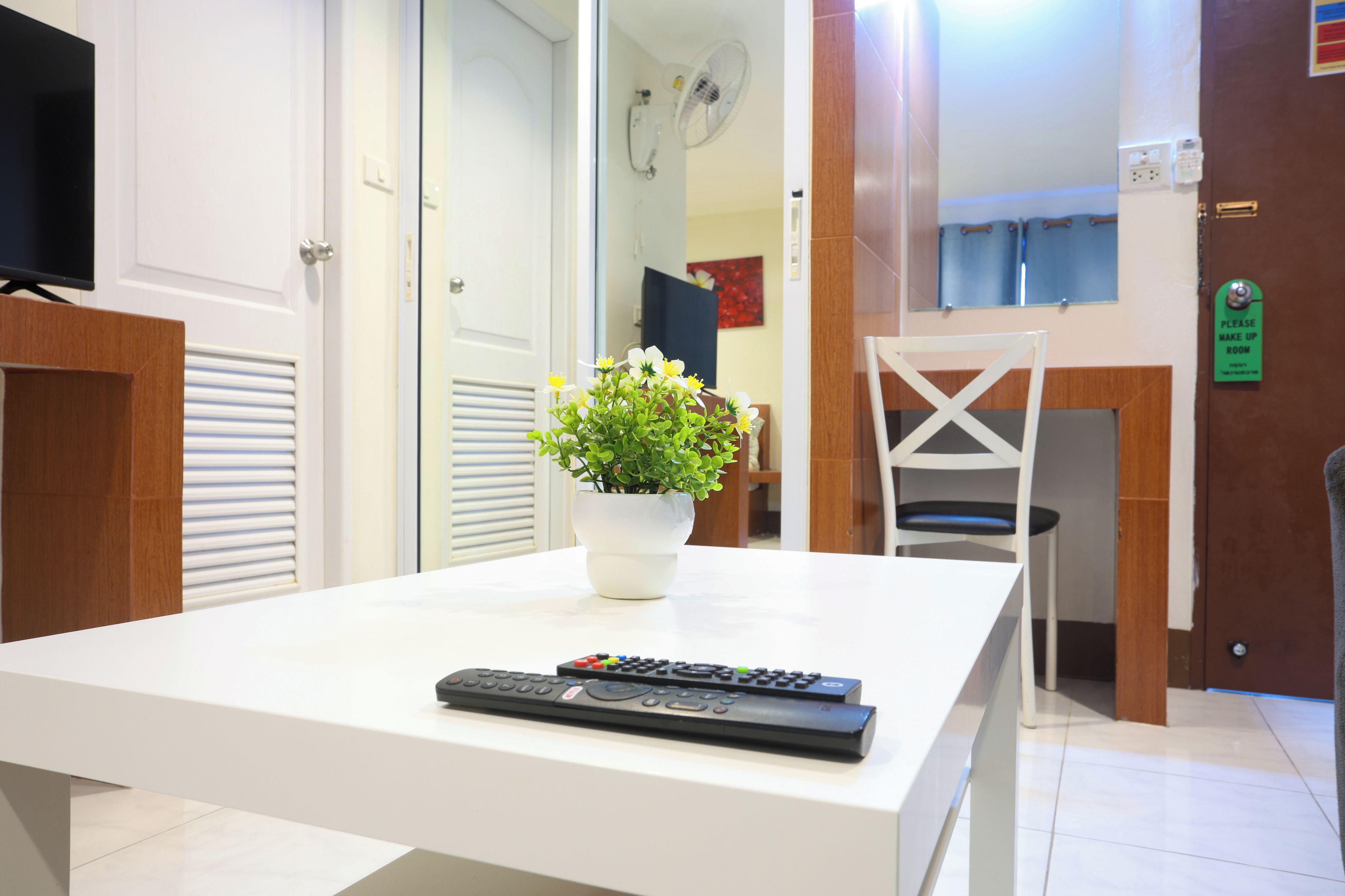 Habitació amb taula blanca, una planta en test i dos mandes a distància.