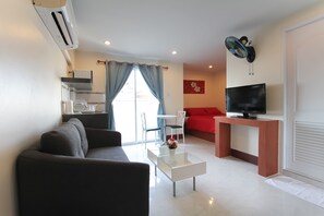 Uma sala de estar moderna com um sofá, uma mesa de centro, uma televisão em um suporte e uma área de jantar com cadeiras e uma mesa.