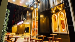 A hotel entrance with a curved facade, illuminated signage, and outdoor seating area. - Baron Zotel Bangkok (Bangkok)