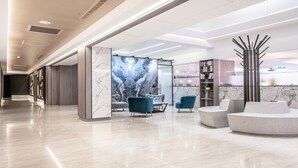 A modern lobby with marble flooring, a reception desk, seating area, and a bookshelf. - Hotel Bonza (Zhubei)