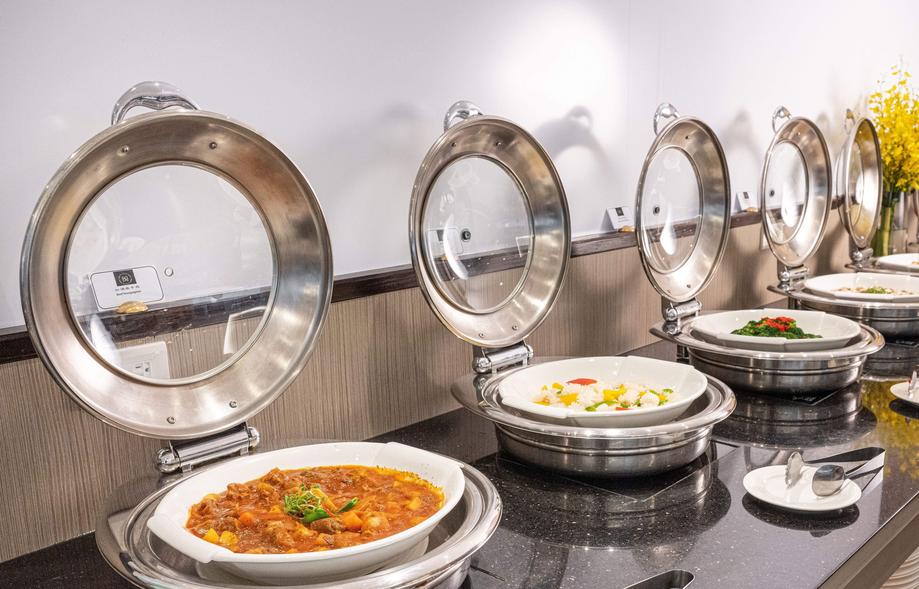 A buffet setup with multiple food stations, each with a covered serving dish.