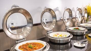 A buffet setup with multiple food stations, each with a covered serving dish.