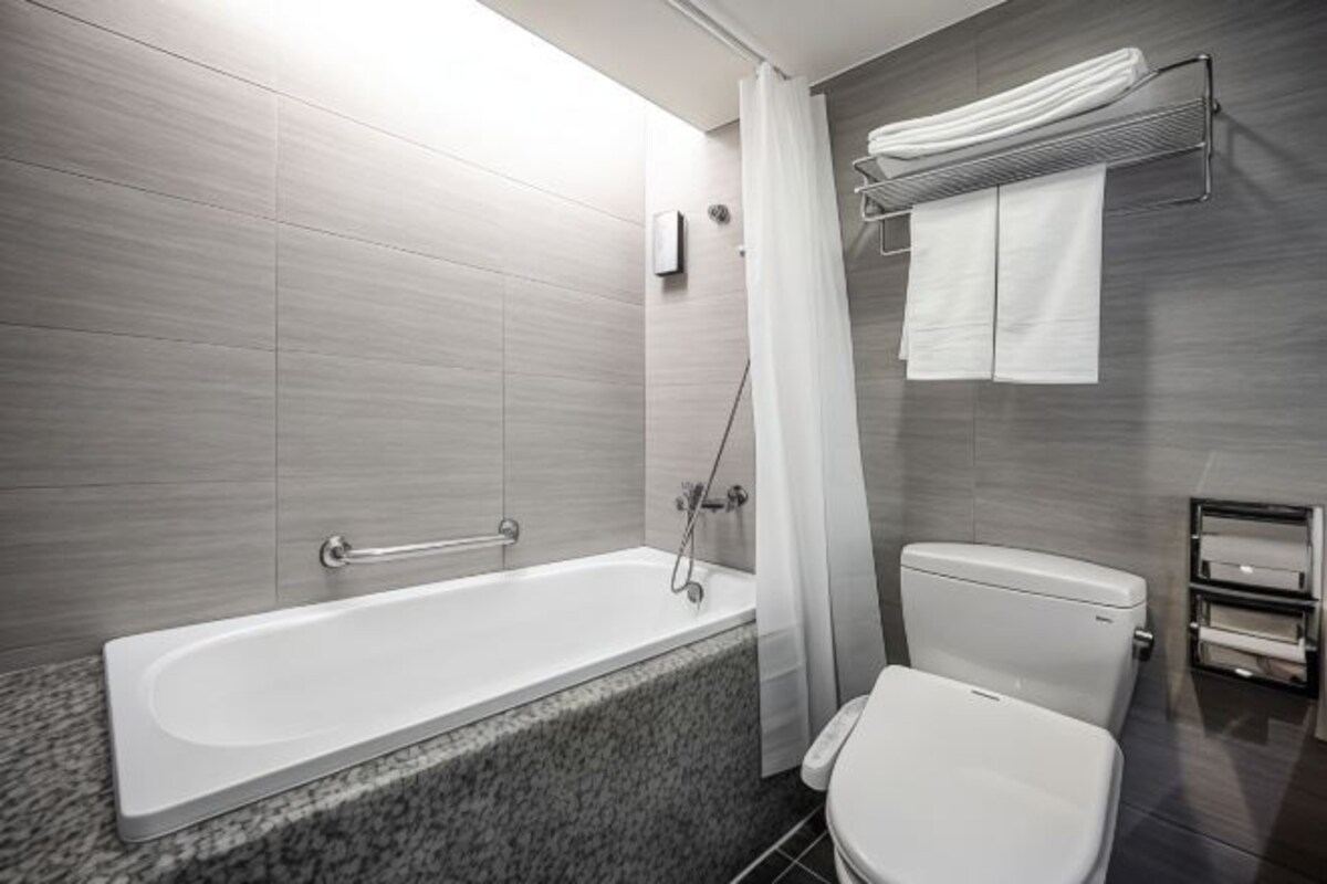 A modern bathroom with a bathtub, toilet, and towel rack.