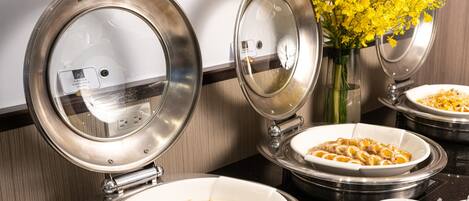 A buffet setup with various dishes, including a bowl of soup and a dish with sliced meat, in a modern kitchen setting.