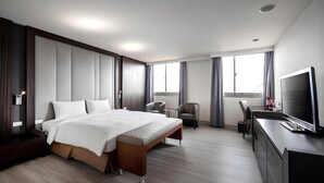 A modern hotel room with a large bed, a desk, a TV, and a view of the city through the windows. - Hotel Bonza (Zhubei)