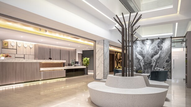 A modern lobby with a reception desk, a marble wall with a tree-like sculpture, and a seating area with a circular bench. - Hotel Bonza (Zhubei)