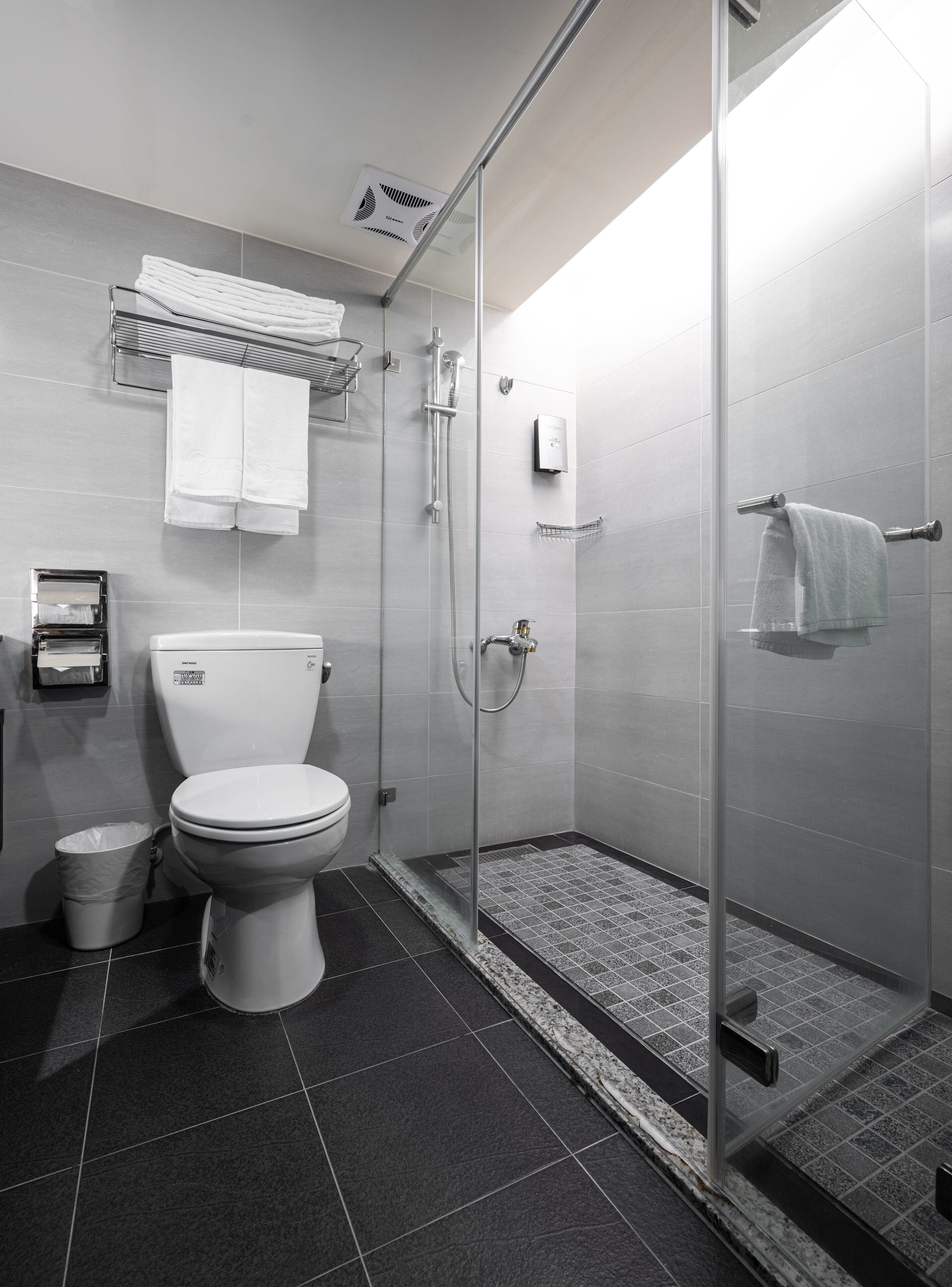 A modern bathroom with a toilet, a glass-enclosed shower, and a towel rack.