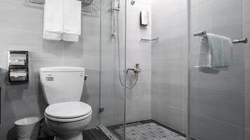 A modern bathroom with a toilet, a glass-enclosed shower, and a towel rack.
