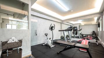 Une salle de sport moderne équipée de matériel d’exercice, d’un banc et d’un panier rempli de serviettes.