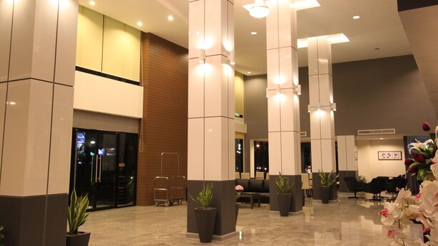 En modern entréhall med högt i tak, stora pelare och en receptionsdisk.