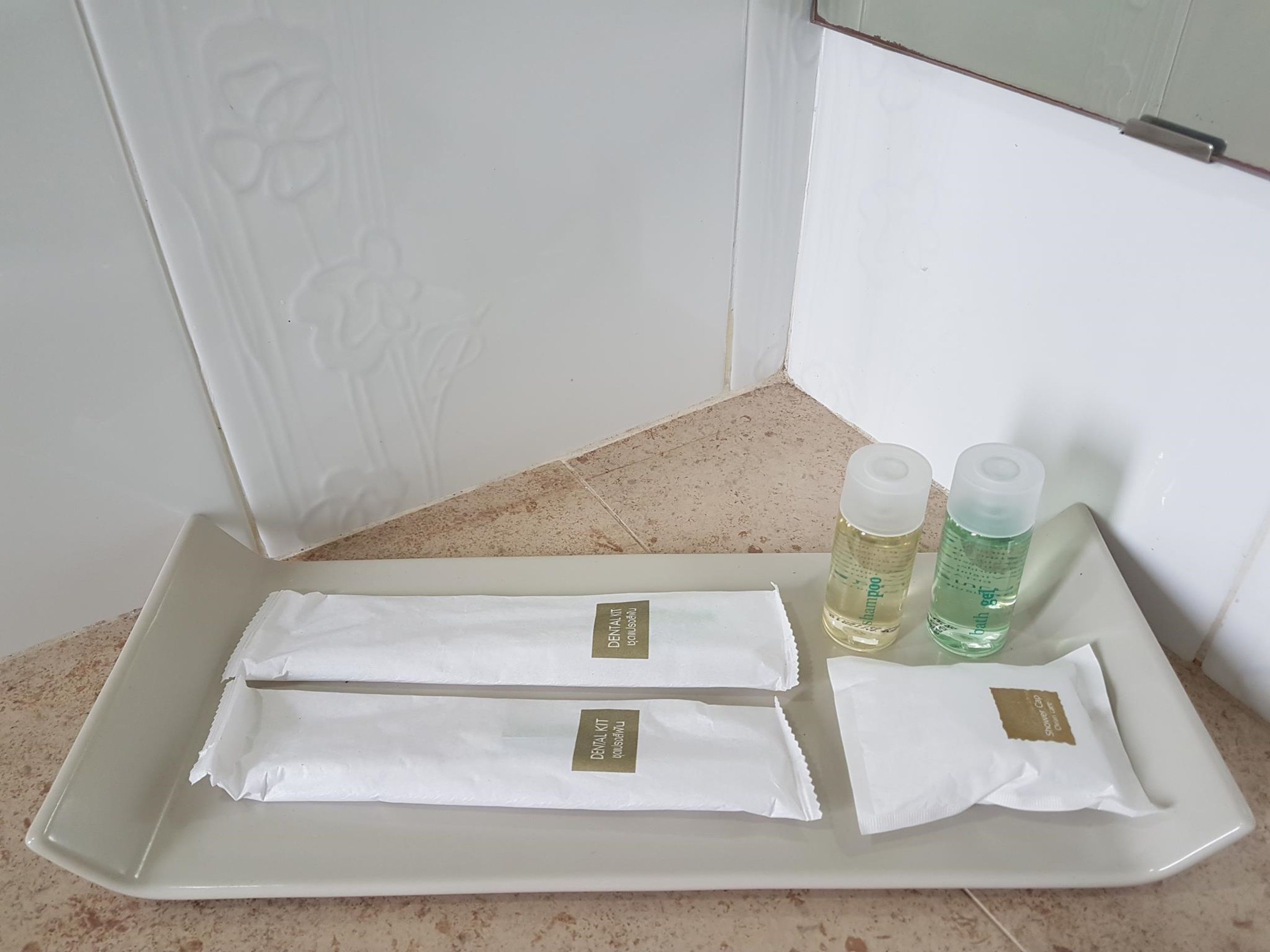 Uma bandeja com produtos de higiene pessoal, incluindo escova de dentes, creme dental e um frasco de shampoo em tamanho viagem.