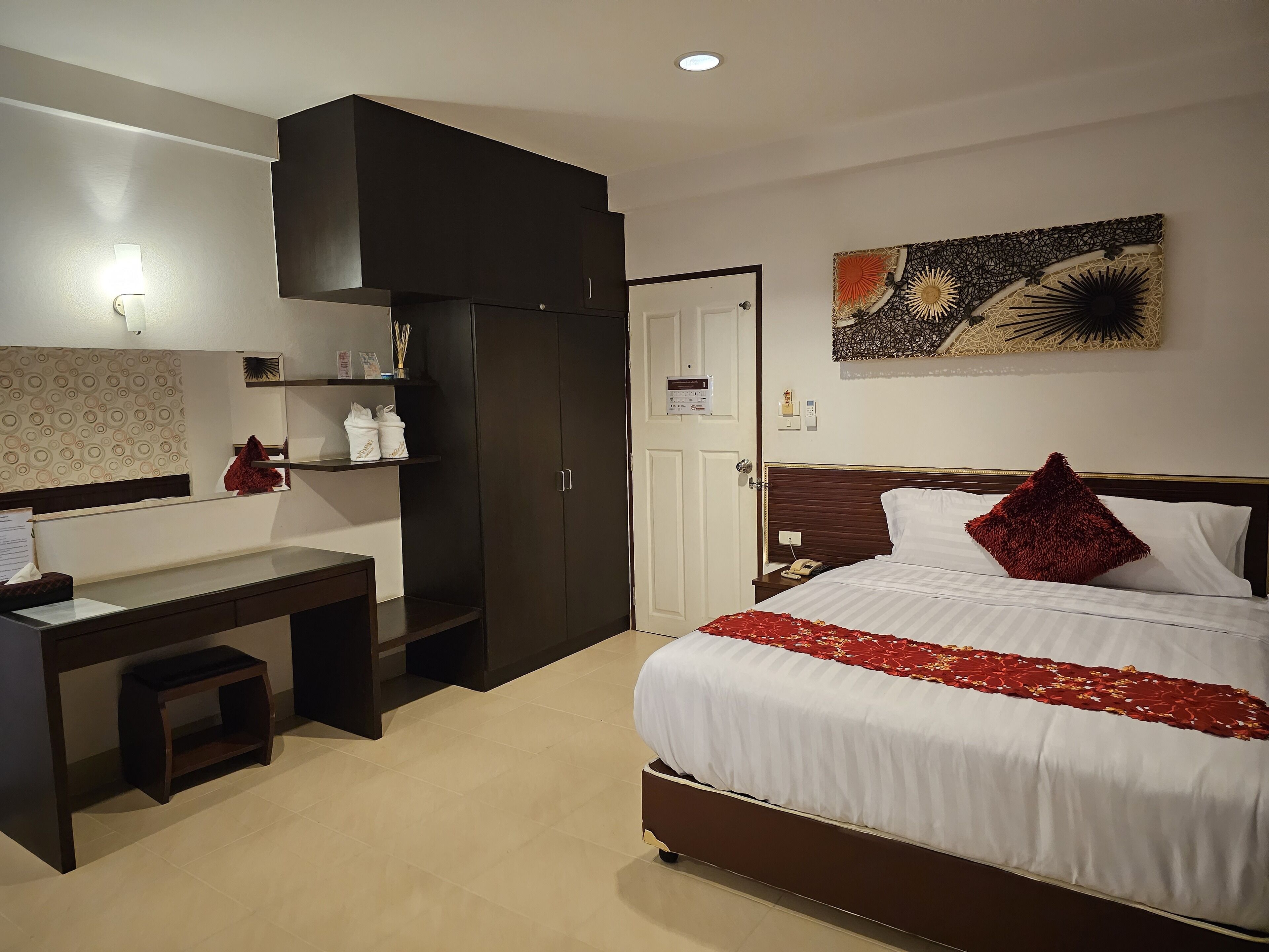 Une chambre d’hôtel comprenant un lit, un bureau, une armoire et une œuvre d’art accrochée au mur.